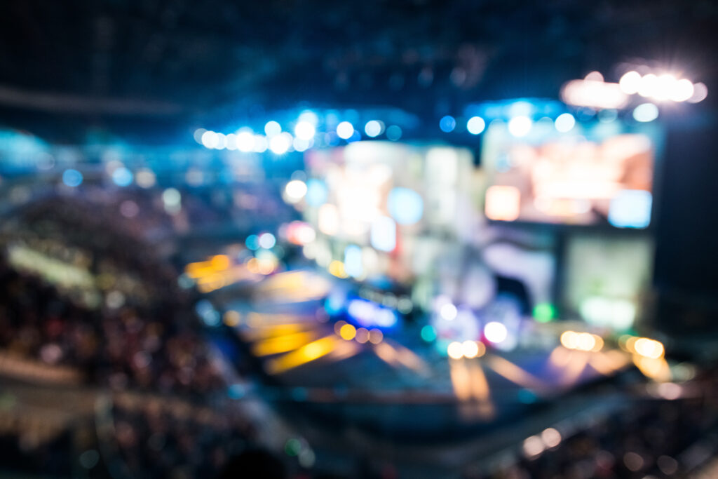 Blurred background of esports event at big arena with a lot of lights and screens